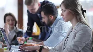 一个年轻漂亮的女孩正在她的笔记本电脑上寻找一些东西，然后在她的平板电脑上做一些笔记。